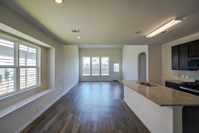 10314 White Fir Villa Ave, Houston, TX 77044 - kitchen with range with gas stovetop, a sink, dark wood-style floors, a kitchen island with sink, and dark stone countertops