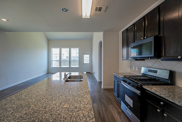 10314 White Fir Villa Ave, Houston, TX 77044 - kitchen featuring stainless steel range with gas cooktop, a sink, baseboards, arched walkways, and tasteful backsplash