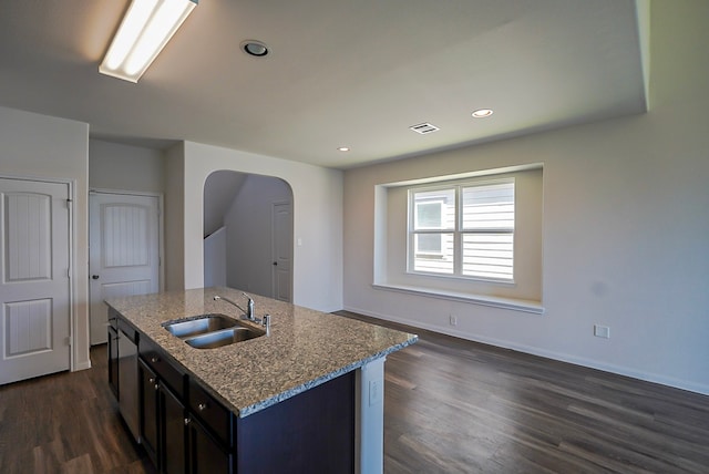 10314 White Fir Villa Ave, Houston, TX 77044 - kitchen featuring a sink, arched walkways, stone countertops, dark wood-type flooring, and baseboards