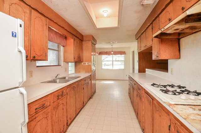 346 9th St, Hempstead, TX 77445 - kitchen with white appliances, a sink, under cabinet range hood, light countertops, and light tile patterned flooring
