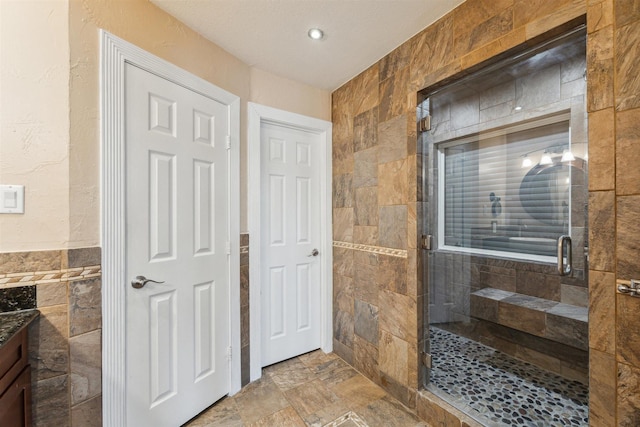 1022 Long Reach Dr, Tiki Island, TX 77554 - bathroom featuring a stall shower, tile walls, vanity, stone finish flooring, and recessed lighting