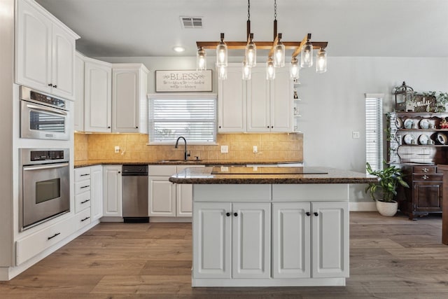 1022 Long Reach Dr, Tiki Island, TX 77554 - kitchen with a sink, wood finished floors, white cabinetry, dark stone countertops, and a center island