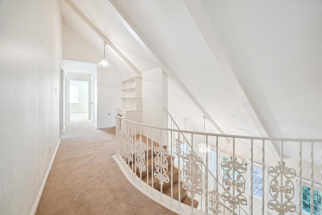 hallway featuring light carpet, baseboards, and lofted ceiling