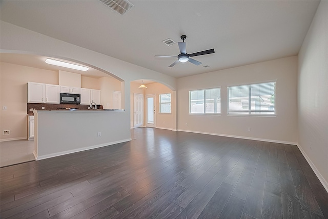 1526 Claremont Garden Cir, Houston, TX 77047 - unfurnished living room featuring a ceiling fan, dark wood finished floors, arched walkways, and baseboards