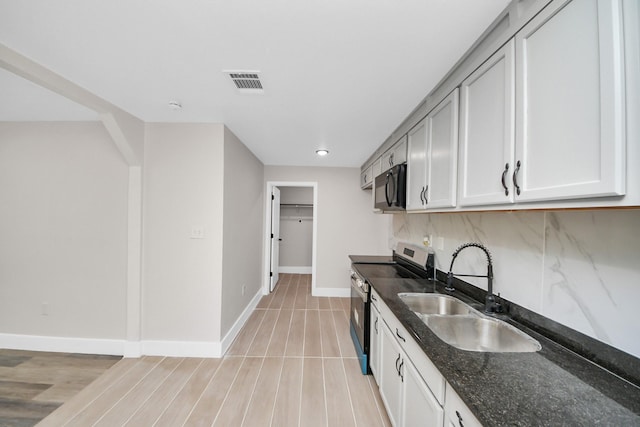 5903 Belneath St, Houston, TX 77033 - kitchen with stainless steel electric range, black microwave, a sink, dark stone counters, and baseboards