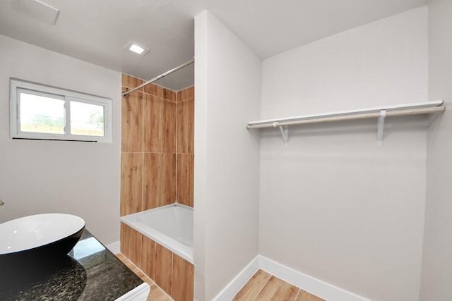 5903 Belneath St, Houston, TX 77033 - bathroom featuring a sink, wood finished floors, shower / bathtub combination, and baseboards