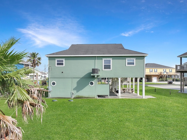 3229 Castle Dr, Crystal Beach, TX 77650 - back of property with a patio area, a yard, roof with shingles, and cooling unit