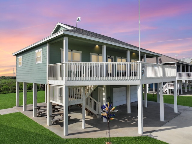 3229 Castle Dr, Crystal Beach, TX 77650 - back of house at dusk with an attached garage, stairs, a lawn, and roof with shingles