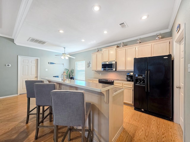 3229 Castle Dr, Crystal Beach, TX 77650 - kitchen featuring black refrigerator with ice dispenser, stainless steel microwave, crown molding, electric range oven, and a breakfast bar area
