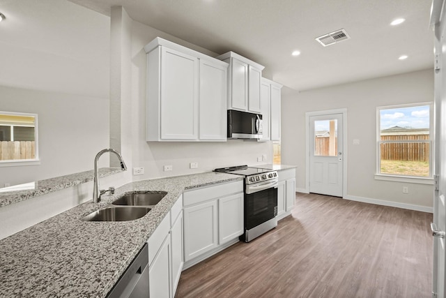 358 Shoreview Dr, Conroe, TX 77303 - kitchen featuring appliances with stainless steel finishes, a sink, light wood-type flooring, recessed lighting, and light stone countertops