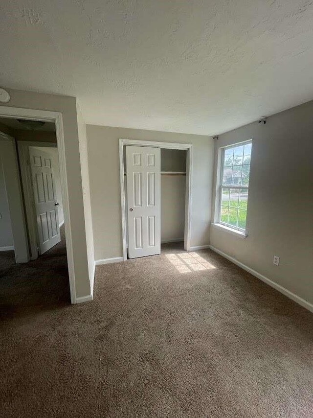 603 Willow St, Baytown, TX 77520 - unfurnished bedroom featuring a textured ceiling, carpet, baseboards, and a closet