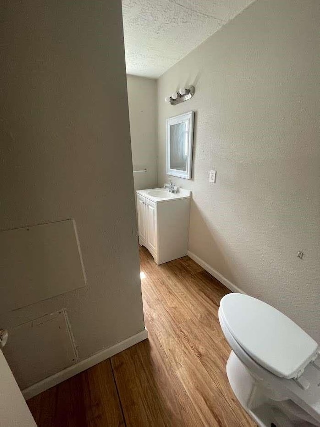 603 Willow St, Baytown, TX 77520 - half bath with wood finished floors, baseboards, toilet, a textured ceiling, and vanity