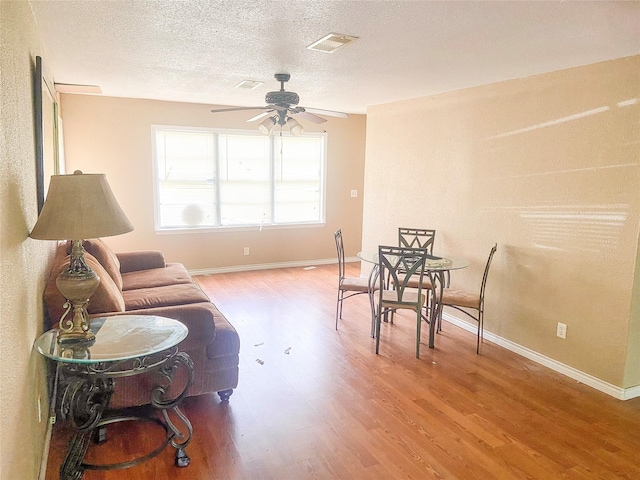 340 Warner St, Bridge City, TX 77611 - living room featuring a ceiling fan, wood finished floors, baseboards, and a textured ceiling