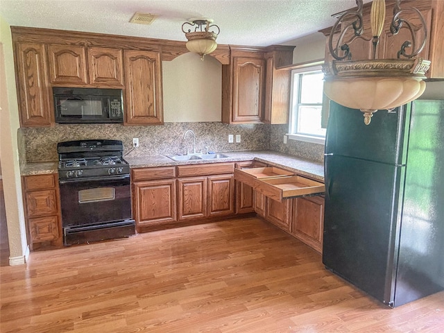 340 Warner St, Bridge City, TX 77611 - kitchen featuring black appliances, a sink, light wood-style flooring, tasteful backsplash, and brown cabinets