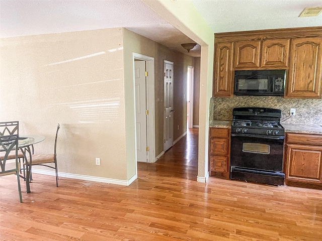 340 Warner St, Bridge City, TX 77611 - kitchen with black appliances, light wood-style floors, baseboards, and brown cabinetry