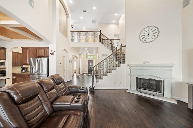 17726 Rough River Ct, Humble, TX 77346 - living area with arched walkways, dark wood finished floors, a tile fireplace, stairway, and a towering ceiling