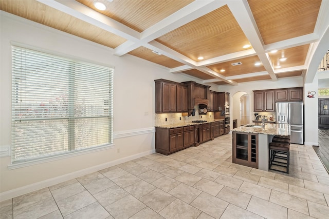 17726 Rough River Ct, Humble, TX 77346 - kitchen with stainless steel fridge with ice dispenser, arched walkways, tasteful backsplash, coffered ceiling, and a kitchen bar