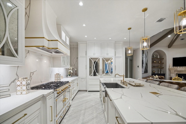 19 Ellicott Way, Sugar Land, TX 77479 - kitchen featuring a sink, custom exhaust hood, open floor plan, stainless steel gas cooktop, and white cabinets
