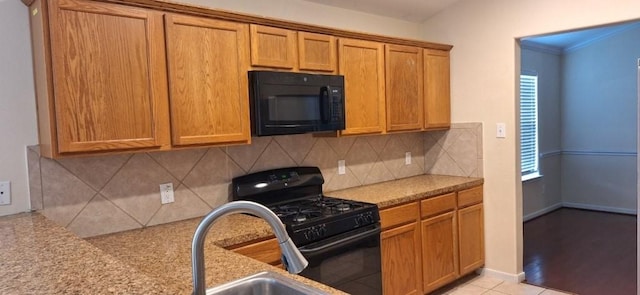 2902 Winslow Forest Ln, Houston, TX 77047 - kitchen with black appliances, tasteful backsplash, brown cabinets, a sink, and light tile patterned flooring