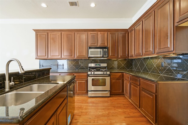 311 Gregg St, Houston, TX 77020 - kitchen with stainless steel appliances, a sink, crown molding, recessed lighting, and dark stone counters