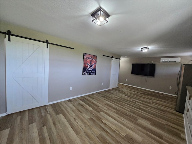 263 Kingfish Ln, Palacios, TX 77465 - below grade area with a barn door, a wall unit AC, freestanding refrigerator, wood finished floors, and baseboards
