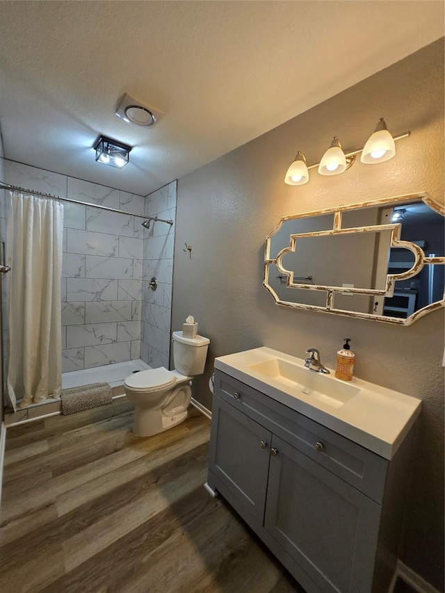 263 Kingfish Ln, Palacios, TX 77465 - bathroom featuring wood finished floors, a stall shower, toilet, vanity, and a textured wall