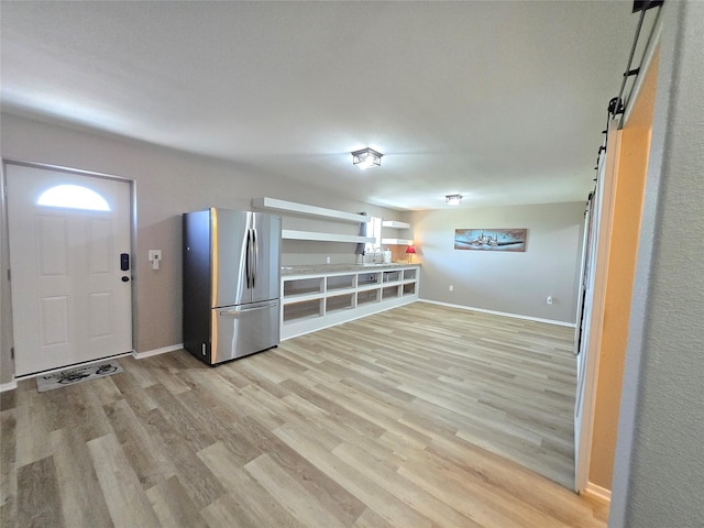 263 Kingfish Ln, Palacios, TX 77465 - kitchen featuring freestanding refrigerator, a barn door, light wood-style floors, and baseboards