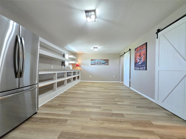 263 Kingfish Ln, Palacios, TX 77465 - interior space with freestanding refrigerator, a barn door, light wood-type flooring, baseboards, and open shelves