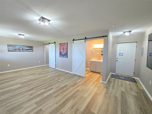 263 Kingfish Ln, Palacios, TX 77465 - foyer entrance with a barn door, light wood-type flooring, baseboards, and a textured ceiling