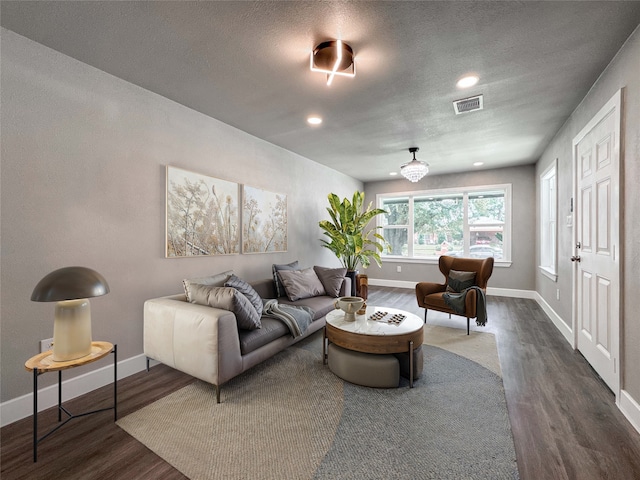 living room with dark wood finished floors, baseboards, a textured ceiling, and recessed lighting
