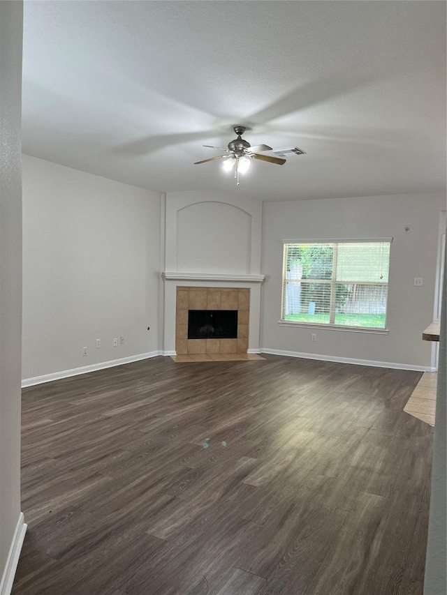 2702 Orchard Creek Ln, Katy, TX 77494 - unfurnished living room with a ceiling fan, a tiled fireplace, dark wood-style flooring, and baseboards