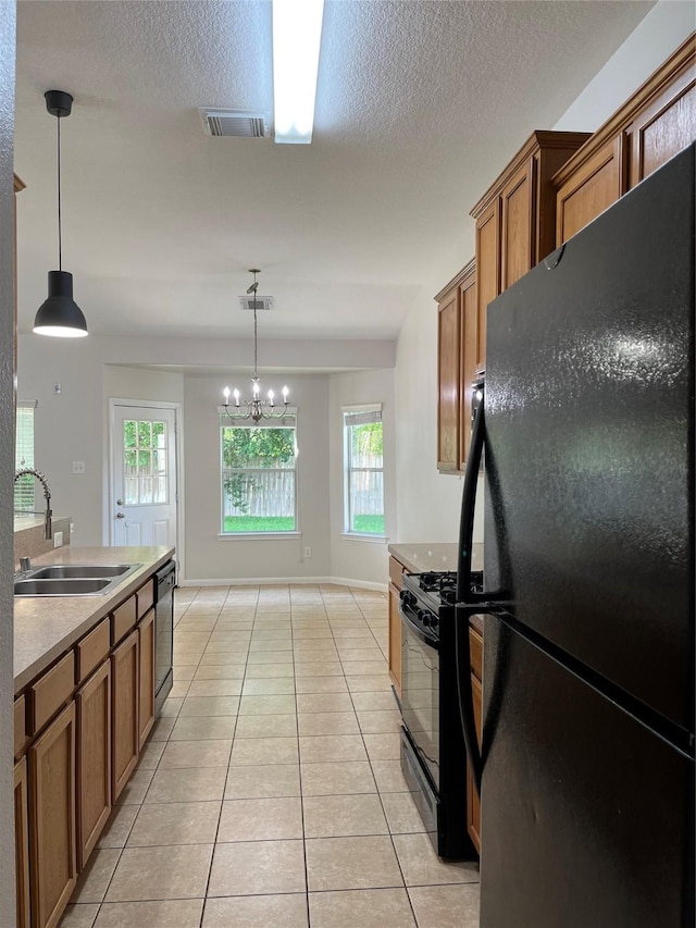 2702 Orchard Creek Ln, Katy, TX 77494 - kitchen featuring black appliances, a sink, brown cabinets, light tile patterned floors, and a textured ceiling