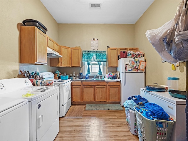 1811 39th St, Galveston, TX 77550 - kitchen with white appliances, under cabinet range hood, washing machine and dryer, a sink, and light wood finished floors