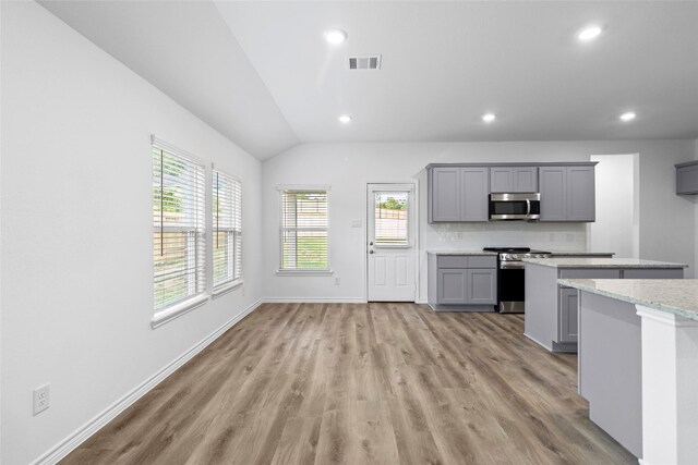 12672 Lake Conroe Hls, Conroe, TX 77318 - kitchen featuring stainless steel appliances, gray cabinetry, light wood-style floors, recessed lighting, and vaulted ceiling