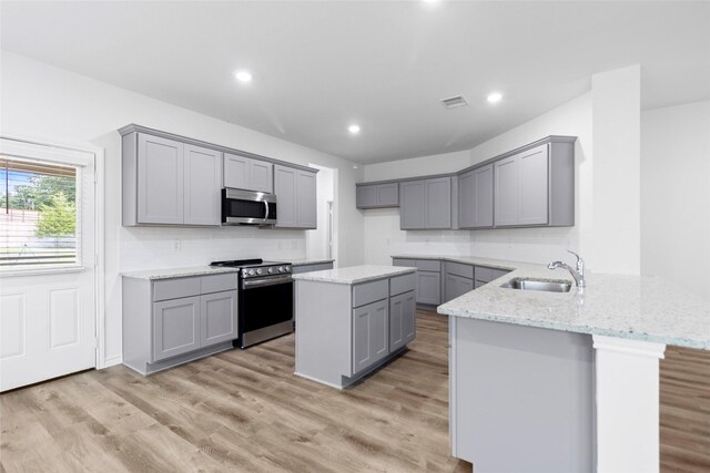 12672 Lake Conroe Hls, Conroe, TX 77318 - kitchen with stainless steel appliances, gray cabinetry, a peninsula, light stone countertops, and recessed lighting