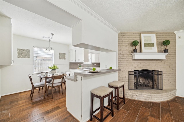 5939 Rutherglenn Dr, Houston, TX 77096 - kitchen with dark wood-type flooring, a sink, white cabinetry, a textured ceiling, and a breakfast bar area