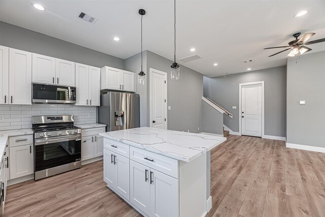 2022 Wavell St, Houston, TX 77088 - kitchen with stainless steel appliances, a ceiling fan, tasteful backsplash, a center island, and light wood-type flooring