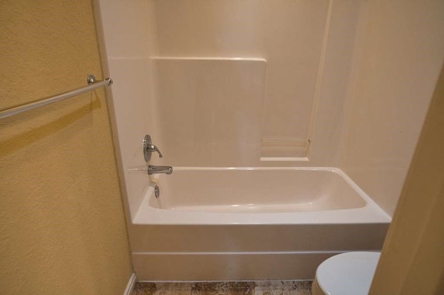 108 Madison Ave, Clute, TX 77531 - bathroom with toilet, washtub / shower combination, and a textured wall