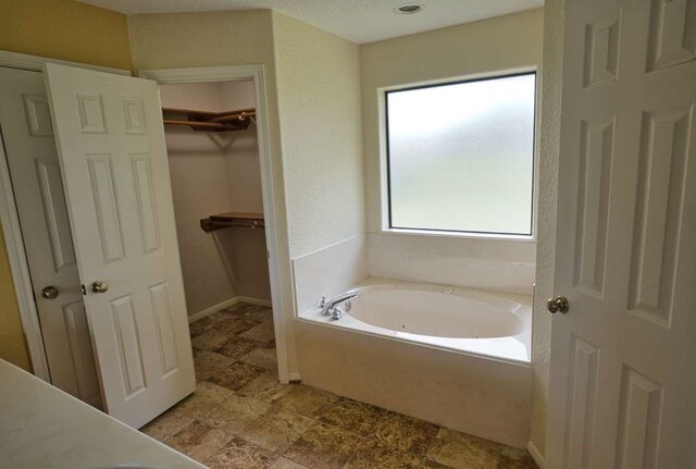 108 Madison Ave, Clute, TX 77531 - bathroom featuring a bath, a walk in closet, and baseboards