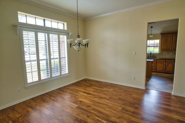 108 Madison Ave, Clute, TX 77531 - unfurnished dining area featuring a chandelier, dark wood finished floors, ornamental molding, a sink, and baseboards