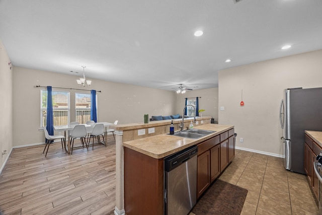 6026 Coleus St, Crosby, TX 77532 - kitchen featuring stainless steel appliances, a sink, a center island with sink, light countertops, and a chandelier