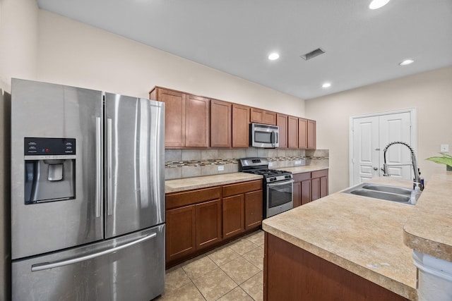 6026 Coleus St, Crosby, TX 77532 - kitchen featuring stainless steel appliances, a sink, light countertops, light tile patterned floors, and brown cabinetry