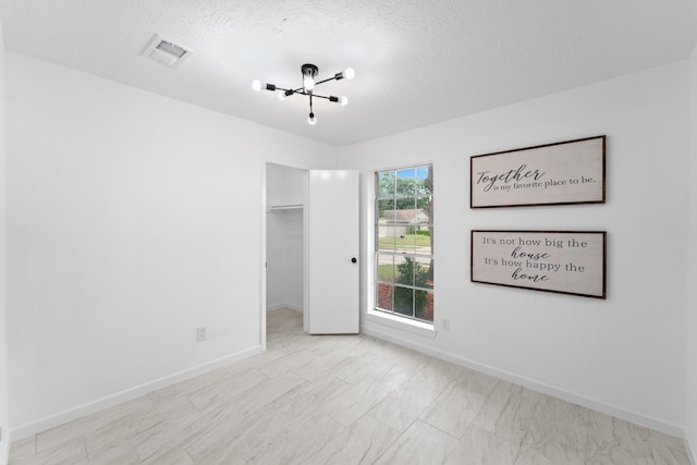 7511 Londres Dr, Houston, TX 77083 - unfurnished bedroom featuring baseboards, a spacious closet, a chandelier, a textured ceiling, and a closet