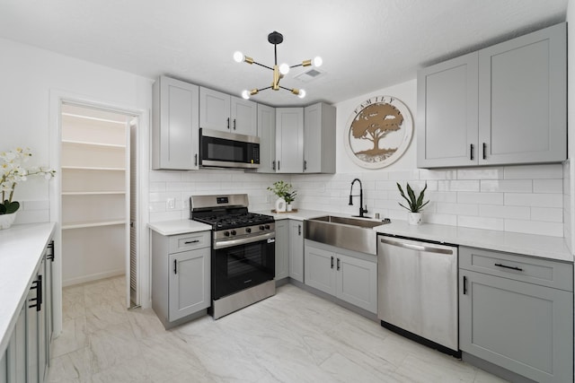 7511 Londres Dr, Houston, TX 77083 - kitchen with appliances with stainless steel finishes, a sink, gray cabinets, and a chandelier