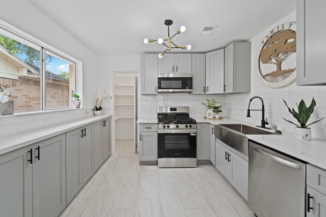 7511 Londres Dr, Houston, TX 77083 - kitchen featuring appliances with stainless steel finishes, a sink, a chandelier, and gray cabinetry