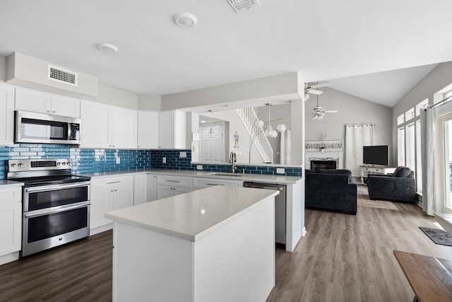 23401 Termini San Luis Pass Rd, Galveston, TX 77554 - kitchen featuring stainless steel appliances, a ceiling fan, a sink, a kitchen island, and a fireplace