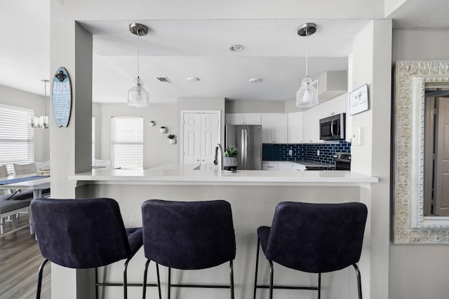 23401 Termini San Luis Pass Rd, Galveston, TX 77554 - kitchen featuring appliances with stainless steel finishes, a breakfast bar, hanging light fixtures, white cabinetry, and light countertops