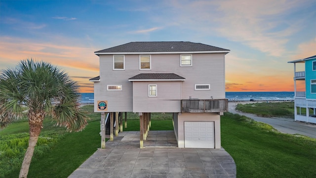 23401 Termini San Luis Pass Rd, Galveston, TX 77554 - back of property at dusk with a carport, concrete driveway, a yard, a water view, and an attached garage