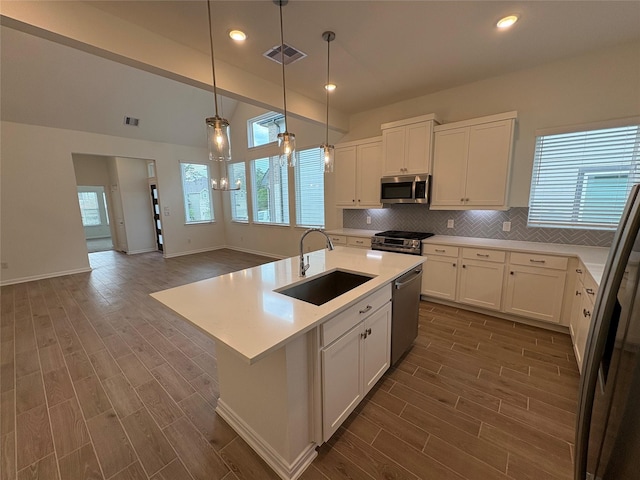 208 Cider Gum Pl, Montgomery, TX 77316 - kitchen with a sink, stainless steel appliances, dark wood-style flooring, backsplash, and light countertops