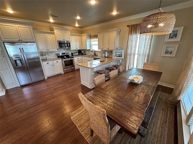 2029 Idyle Vw, Crystal Beach, TX 77650 - kitchen featuring appliances with stainless steel finishes, a peninsula, dark wood-style flooring, backsplash, and ornamental molding